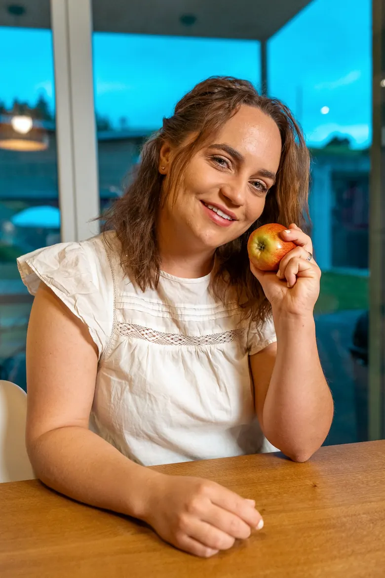 Norina Kreier-Fäh sitzt am Tisch, einen Apfel in der Hand